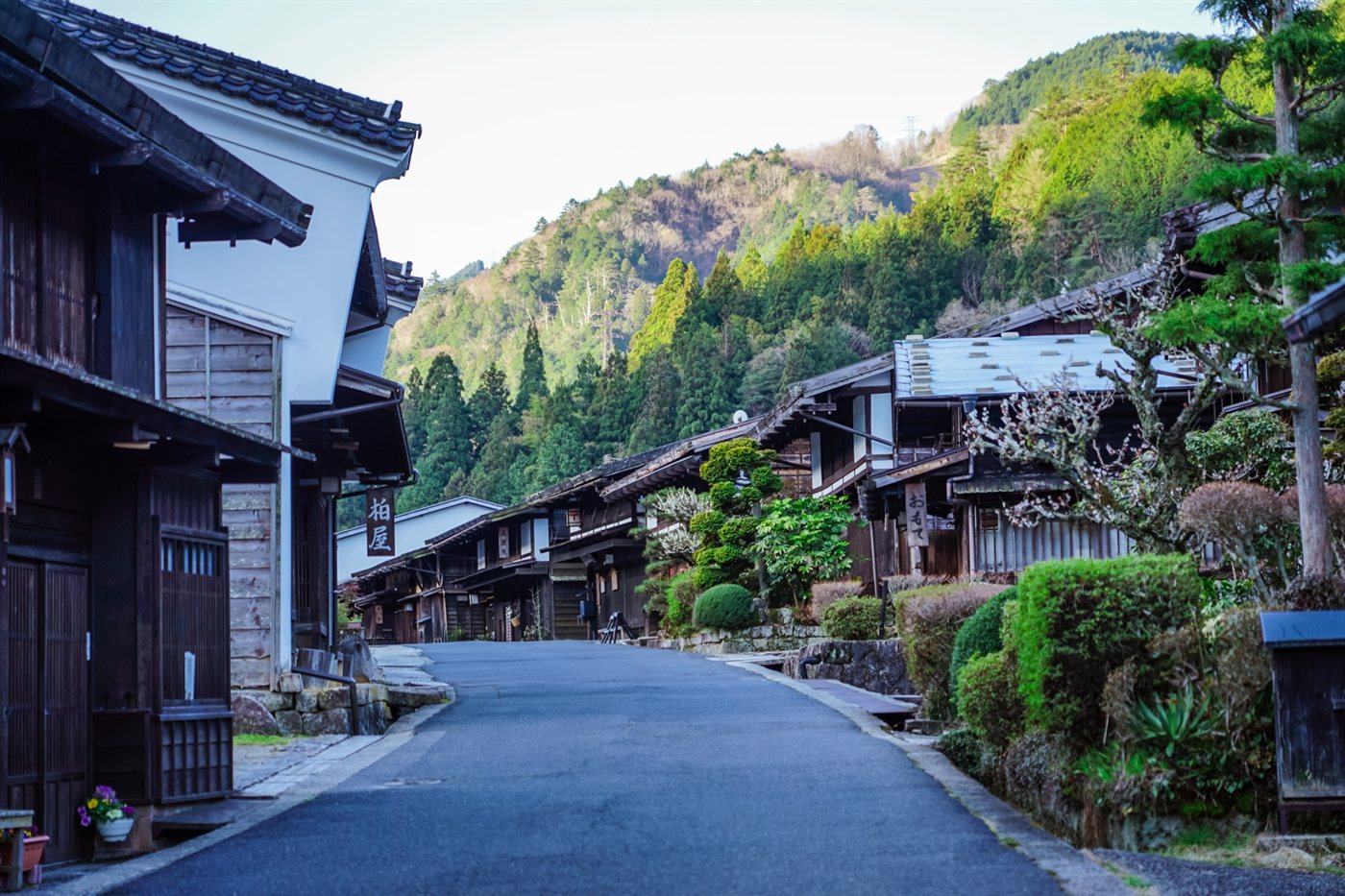 山を背景に古い木造の家が並ぶ妻籠宿の町並み